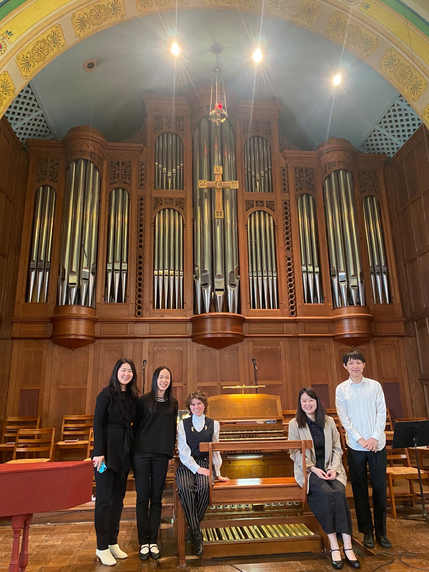 Yi-Hui Chen with colleagues in front of a large pipe organ in a church