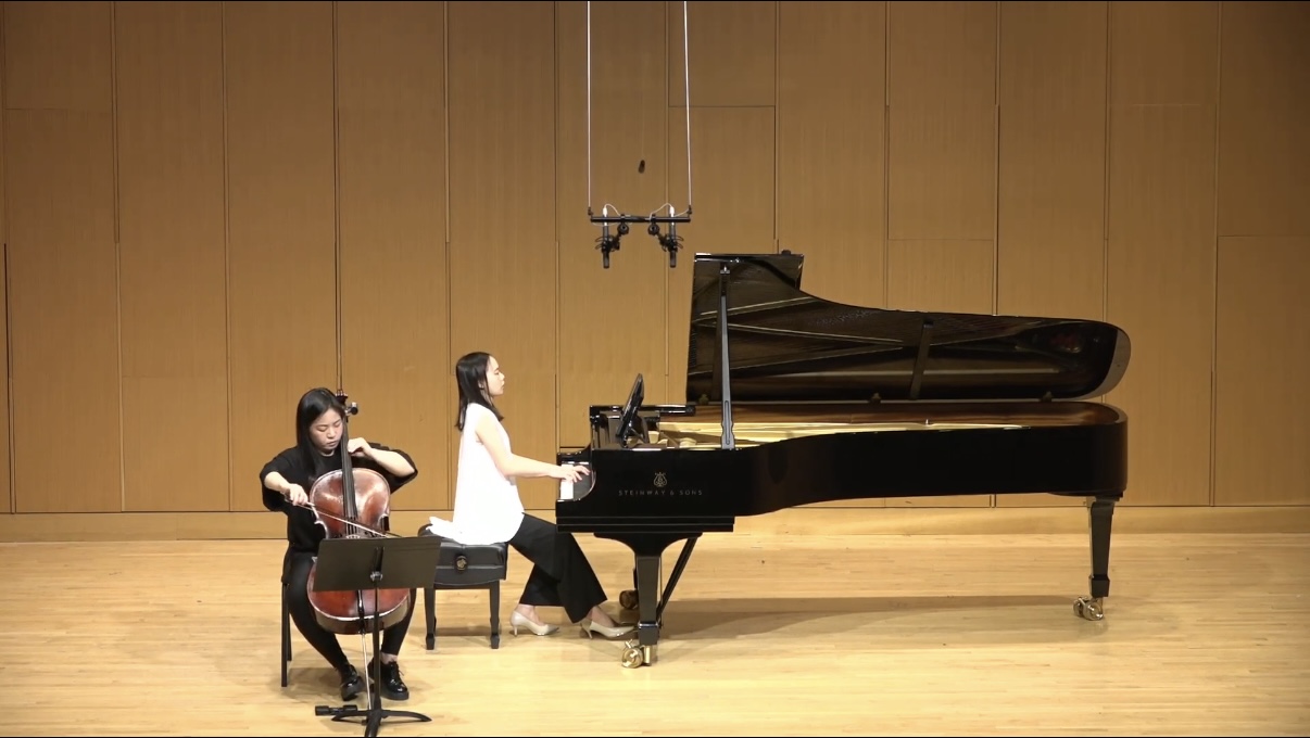 Yi-Hui Chen at the piano performing with a cellist on a concert stage