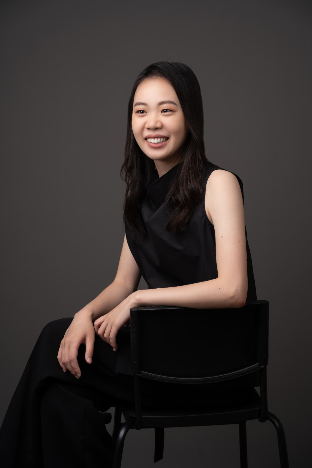 Studio portrait of Yi-Hui Chen seated on a chair, smiling