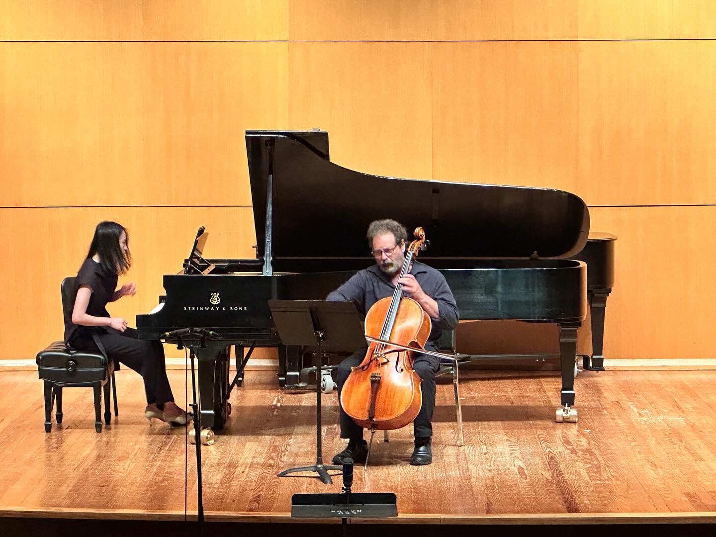 Yi-Hui Chen at the piano performing with a cellist on a wood-panelled concert stage