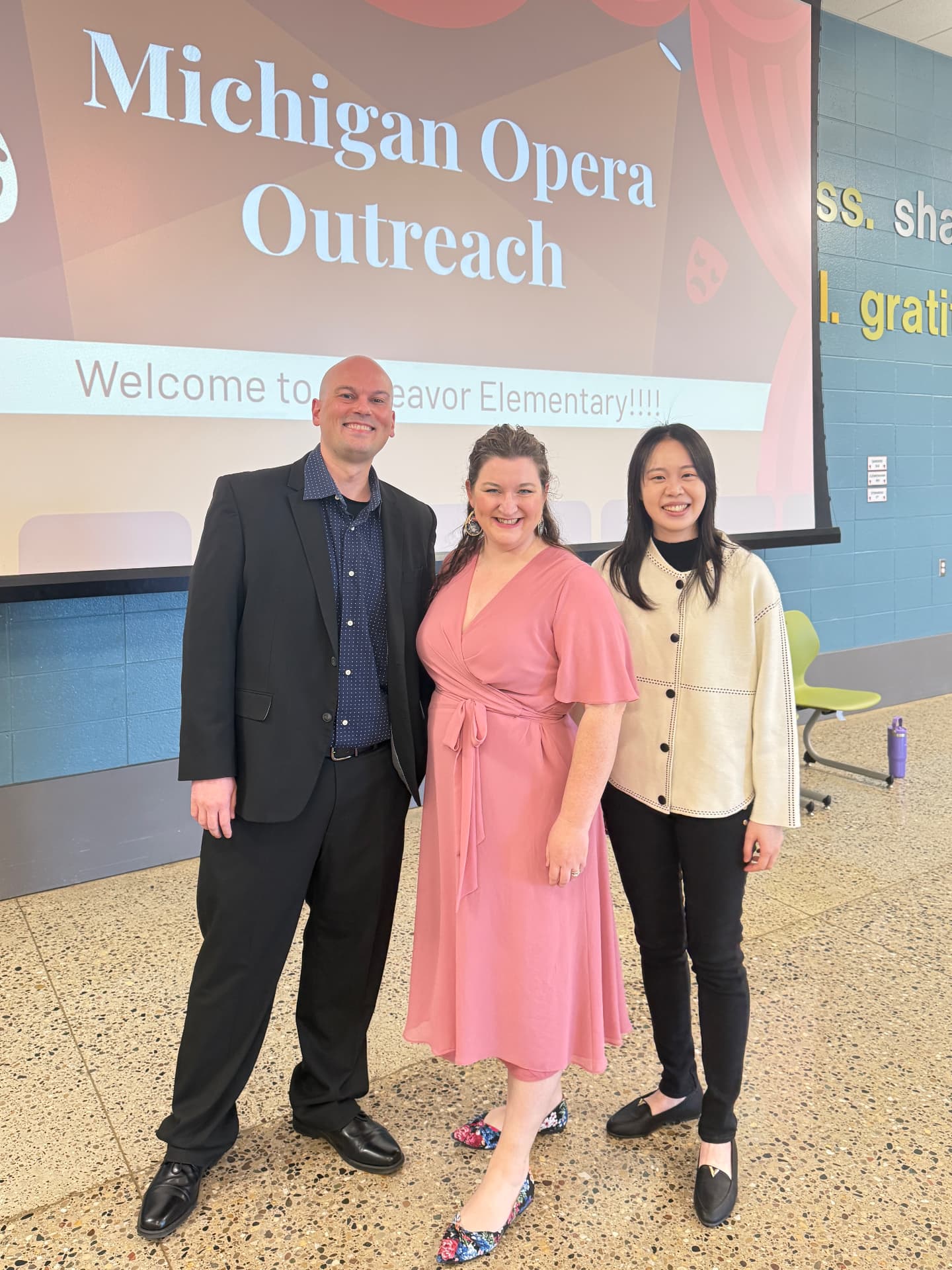 Yi-Hui Chen with Michigan Opera Outreach artists in front of a presentation screen