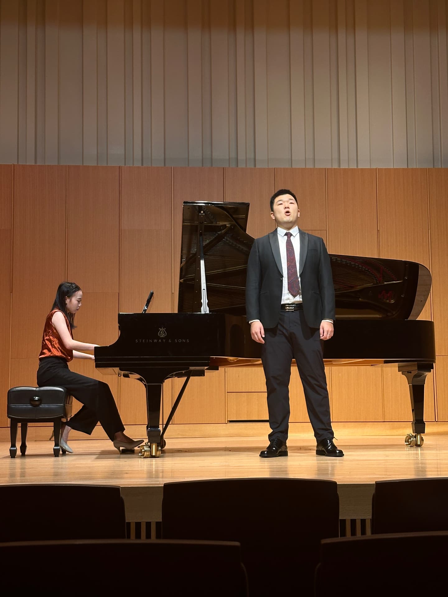Yi-Hui Chen at the piano accompanying a male vocalist in a recital hall