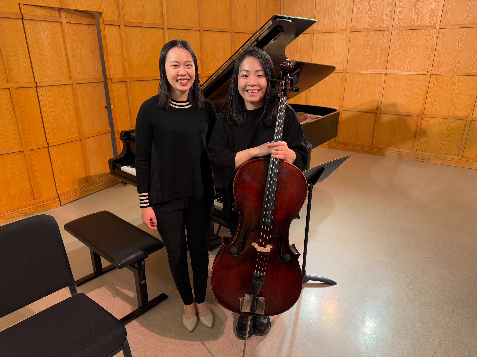 Yi-Hui Chen standing beside a cellist in front of a grand piano in a wood-panelled hall