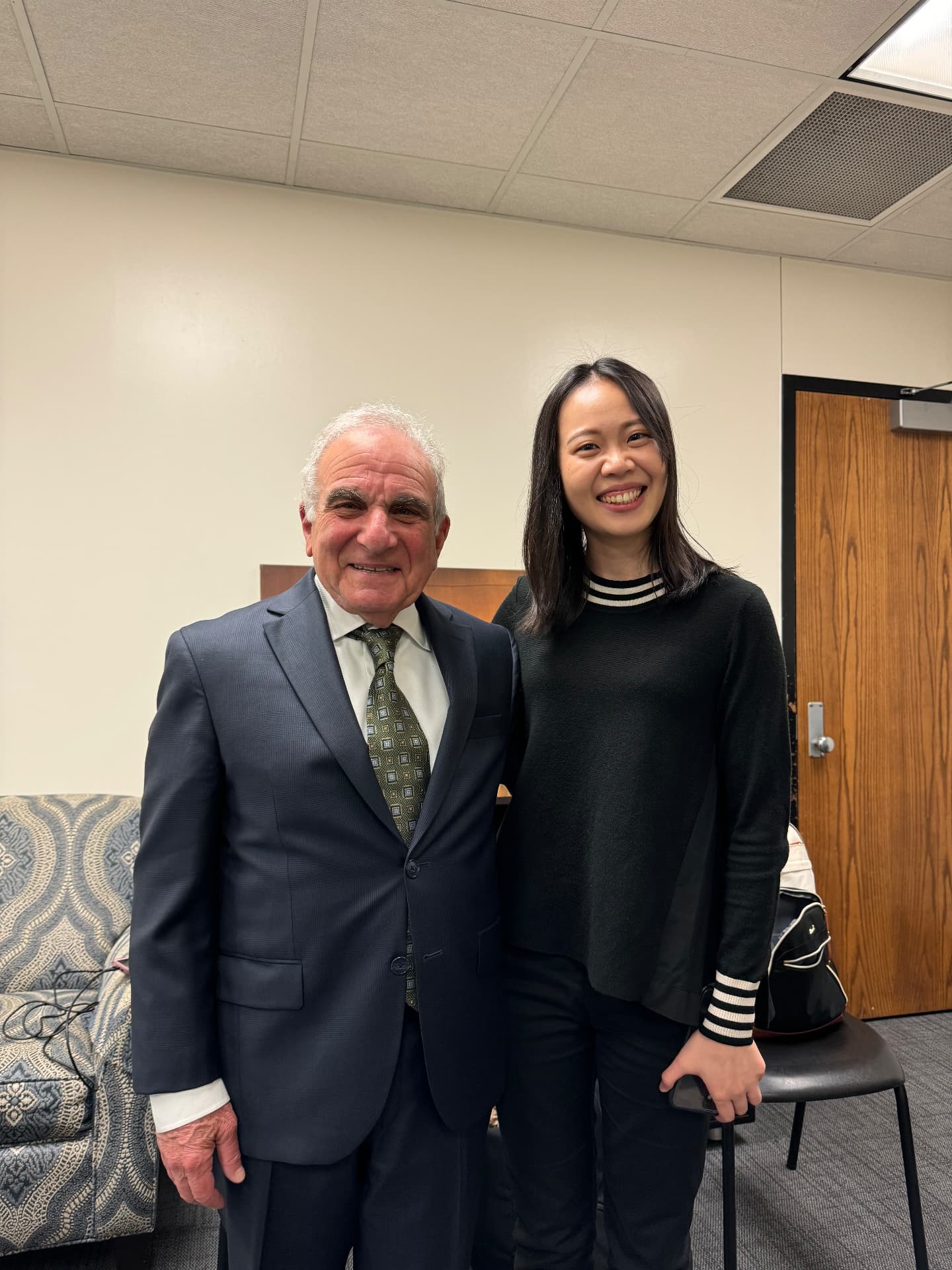 Yi-Hui Chen backstage smiling beside a distinguished senior pianist in a suit