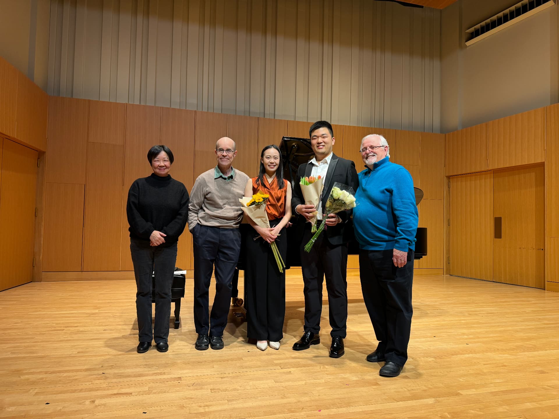 Yi-Hui Chen on stage holding flowers with four colleagues and supporters after a concert